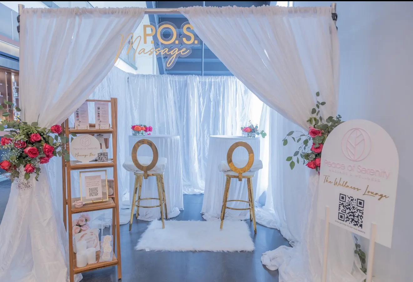 The Peace of Serenity Wellness Lounge with white drapes, pink flowers and two gold chairs