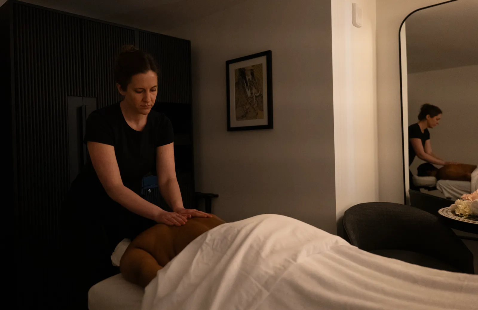 A Peace of Serenity therapist giving an in-room massage to a guest in a hotel room
